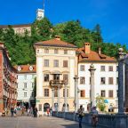 Ljubljana, Slovenia - April 27, 2018: People on Triple Bridge and Old castle on Castle hill in the historical center of Ljubljana, Slovenia